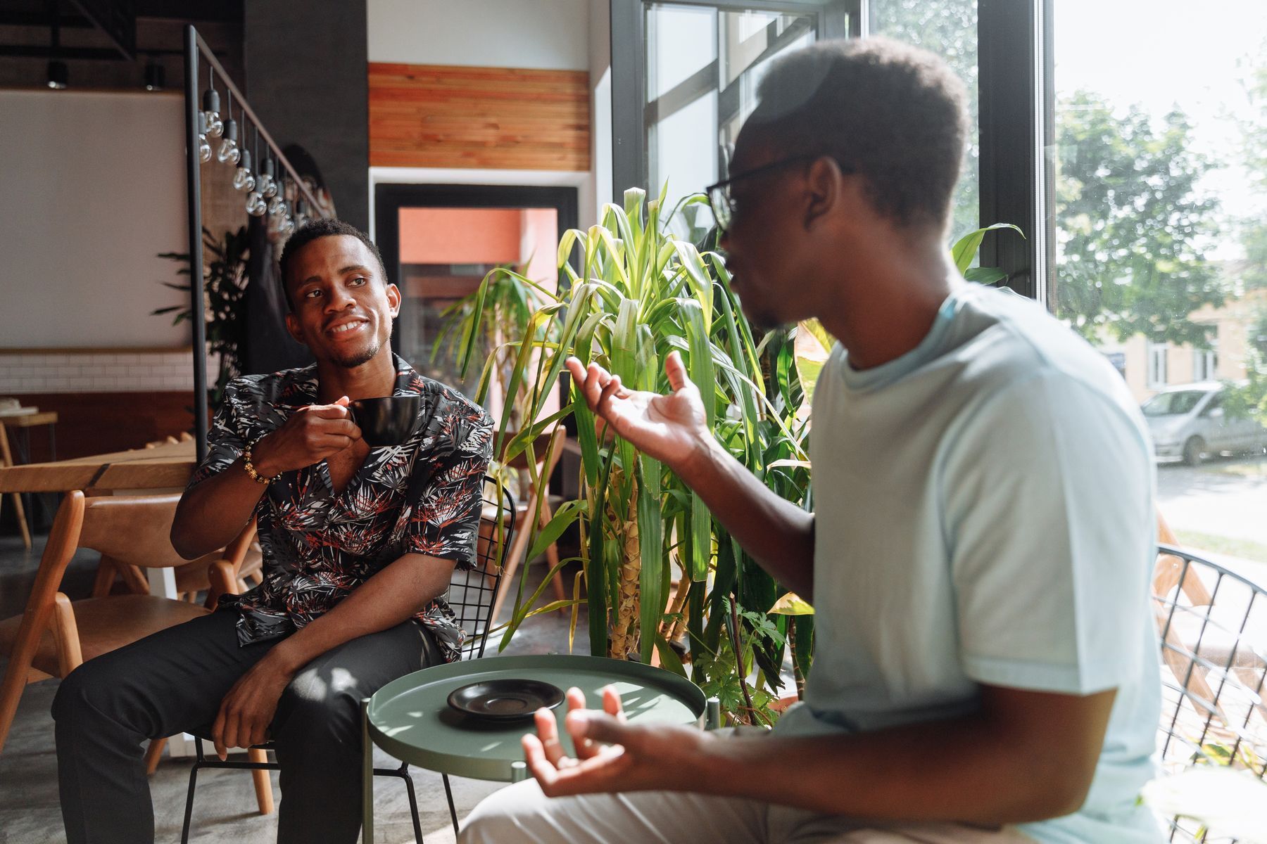 Two friends talking over coffee by a window