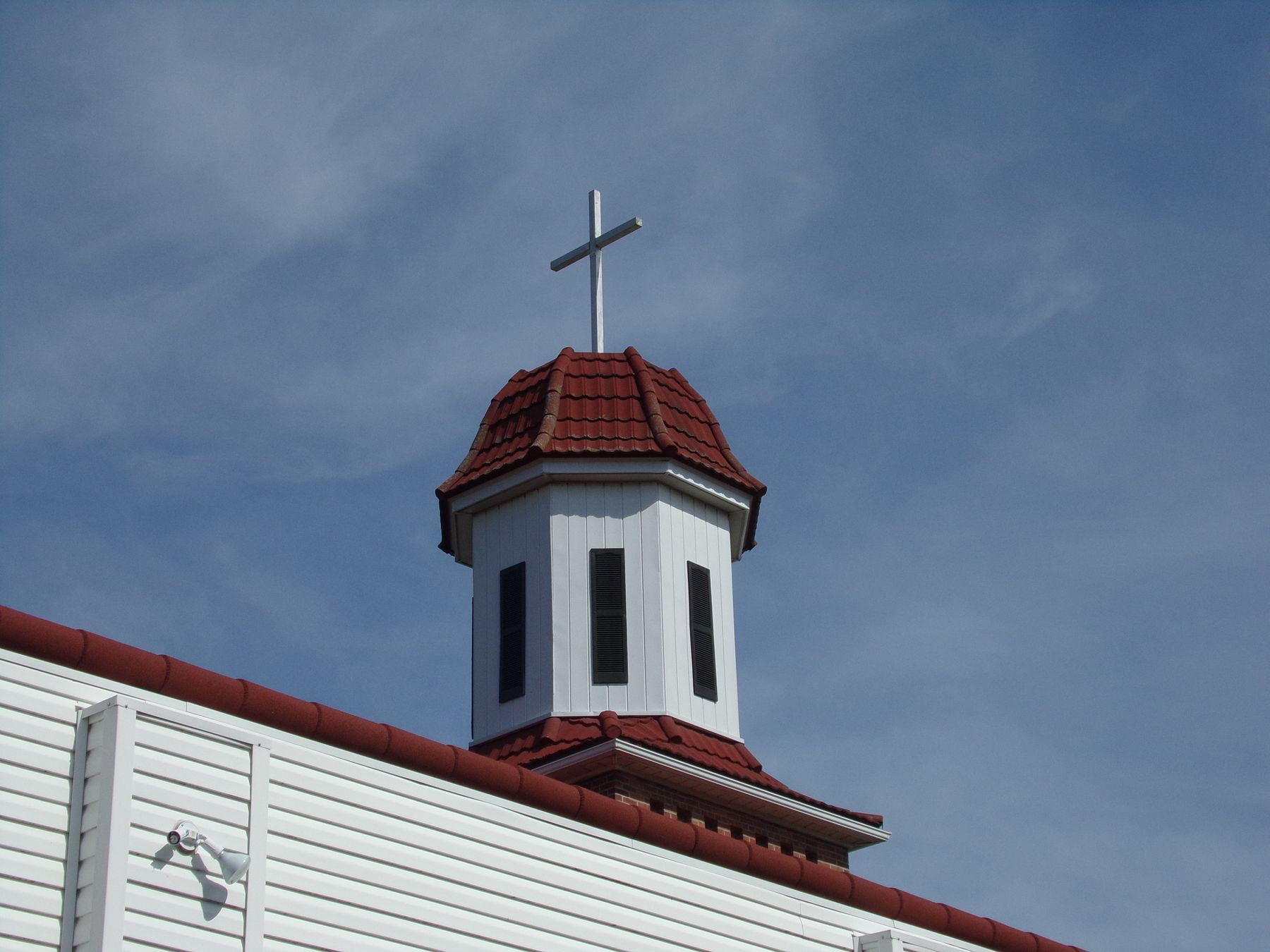 A white steeple with a red roof and a cross